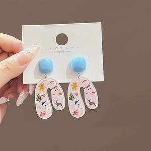 Detail of Christmas themed U-shaped acrylic earrings with colorful festive patterns