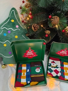 Close-up of two pairs of cotton Christmas socks with Santa Claus patterns in a gift box