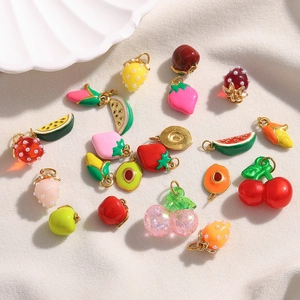 Detail of assorted fruit pendants like strawberry and watermelon on beige satin fabric
