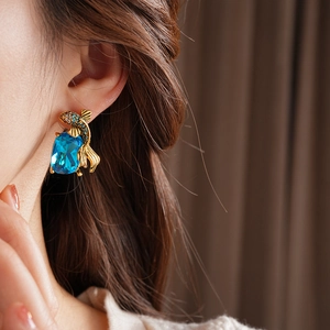 Detail of vintage gold koi fish earrings with blue gemstone and sparkling crystals
