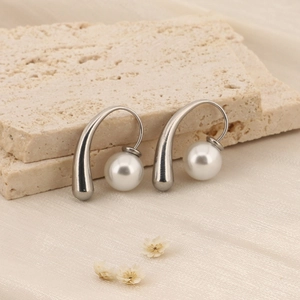 Boucles d'oreilles vintage en argent avec perles blanches sur fond de pierre beige