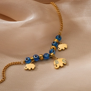Bracciale di perline dorate con ciondoli a elefante e occhio azzurro su seta beige