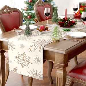 Christmas table runner with gold snowflake patterns on beige linen in festive dining setting