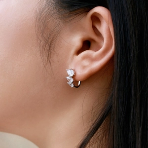 Close-up of S925 silver hoop earrings with three pear-cut zircon stones on a model