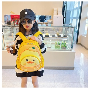 Detail of cute yellow 3D duck cartoon backpack worn by a young girl in a modern cafe