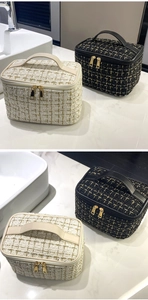 Detail of tweed quilted makeup bags in black and white with gold double zippers and handles