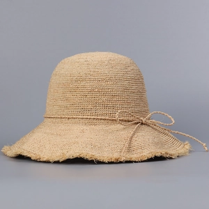 Detailed close-up of handmade straw hat with woven bow and fringe brim texture