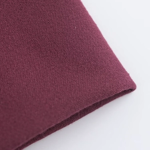 Gros plan du tissu tricoté bordeaux montrant la texture et la qualité du matériau
