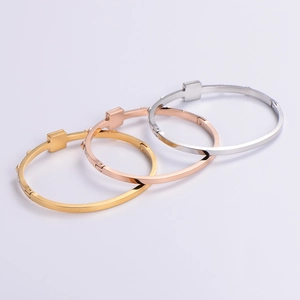 Three 18K square diamond bangles in gold, rose gold and silver on a grey backdrop