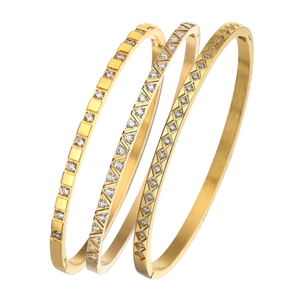 Three gold stainless steel bangles with diamond patterns on white background