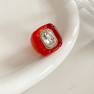 Détail d'une bague vintage en résine rouge avec cristaux sur une assiette en porcelaine