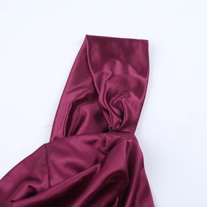 Détail du tissu en satin bordeaux avec une texture plissée élégante et des coutures drapées