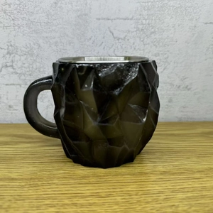 Detail view of the black geometric coffee mug with a built-in metal tea strainer