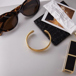 Detailed flat lay of golden lace cutout bangle with lifestyle fashion accessories