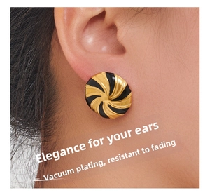 Close-up of golden spiral earrings with black enamel featuring vacuum plating process
