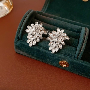 Close-up of crystal floral leaf stud earrings in dark green velvet jewelry box