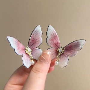 Detail of butterfly earrings with pink gradient wings and hanging white pearls