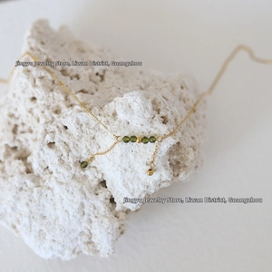 Close-up of olive green crystal beads on 18K gold plated titanium necklace