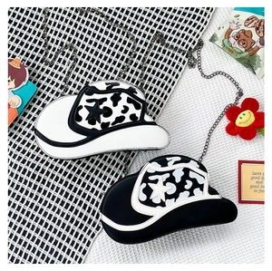 Detailed top view of two cowboy hat shaped crossbody bags with cow print and star accents