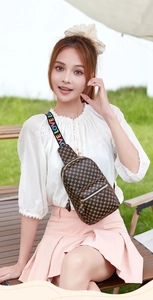Detail of a deep brown crossbody bag with LOVE patterned strap on a model outdoors