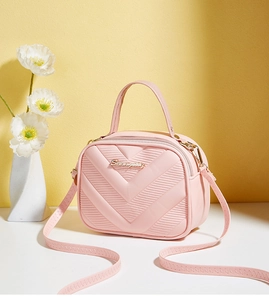 Close-up of pink crossbody bag featuring V-quilted pattern and gold metal hardware
