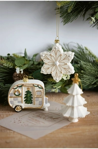 Close-up of cream and gold Christmas ornaments featuring snowflakes and vintage camper