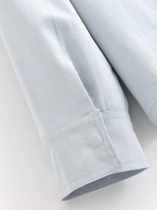 Close-up of light blue shirt sleeve cuff showing detailed twill fabric texture and stitching