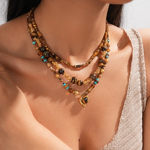 Close-up of layered beaded necklace with tiger eye stones and a golden heart pendant