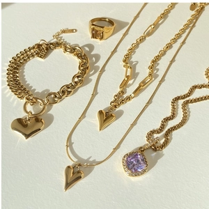 Flat lay of gold-plated heart pendant necklaces and jewelry set on a beige background