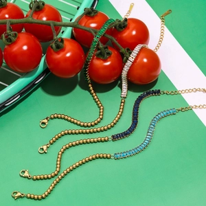 Macro view of gold-plated bracelets featuring rectangular gemstones and beaded chains
