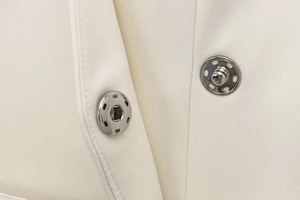 Detailed macro view of silver snap buttons on high-quality white twill blazer fabric