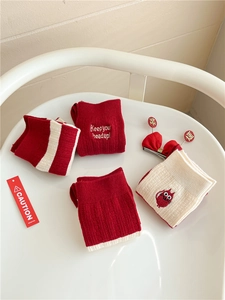 Detail of red and cream festive socks with embroidery and stripes on a white stool