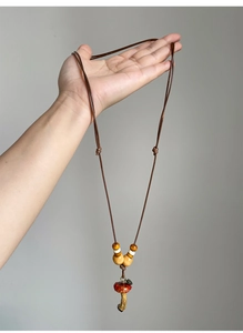 Close-up of handmade wooden bead mushroom pendant necklace with a red ceramic charm