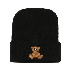 Close-up of a black knit beanie featuring a cute brown bear embroidery on the folded cuff