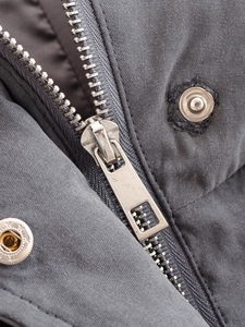 Close-up of industrial silver zipper and snap buttons on a grey parka jacket fabric