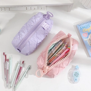 Detail of quilted cotton pencil cases with oversized zippers in soft pink and purple colors