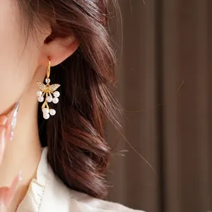 Elegante 18K vergulde vlinder oorbellen met witte parel clusters gedragen door een model
