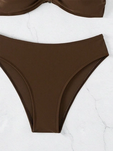 Vista detallada de la tela marrón del bikini con textura acanalada sobre fondo mármol