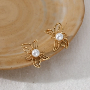 Exquisite gold stainless steel butterfly earrings with white pearl centers on ceramic