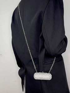 Silver mini rhinestone lipstick chain bag worn crossbody over a black blazer