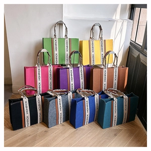 Stack of colorful felt tote bags featuring MOMPICK lettered straps in various vibrant colors