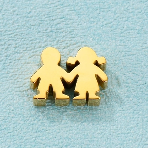 Macro shot of gold-plated boy and girl cartoon charms on a light blue textured surface