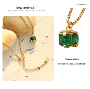 Detailed view of gold 18K necklace with square emerald zircon pendant on stone background