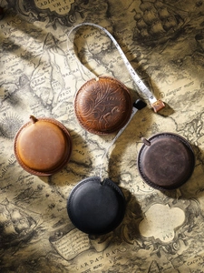 Top view of vintage leather tape measures in four colors on a nautical map background