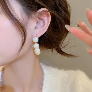 Elegant French vintage gold hook earrings with three white pearls on a model
