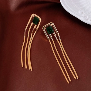 Detail of emerald green zircon earrings with long golden tassels on silk fabric