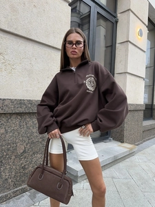 Close-up of the vintage chest print on a dark brown half-zip long sleeve sweatshirt