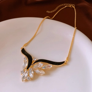 Close-up of golden wing pendant necklace with black enamel and sparkling rhinestones