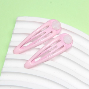 Detail view of two hollow pink snap hair clips on a wavy white minimalist stand