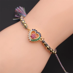 Macro detail of adjustable woven bracelet with colorful zircon heart and gold beads